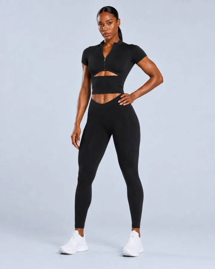 Black zip-front cutout crop top with V-waist pocket leggings — front view